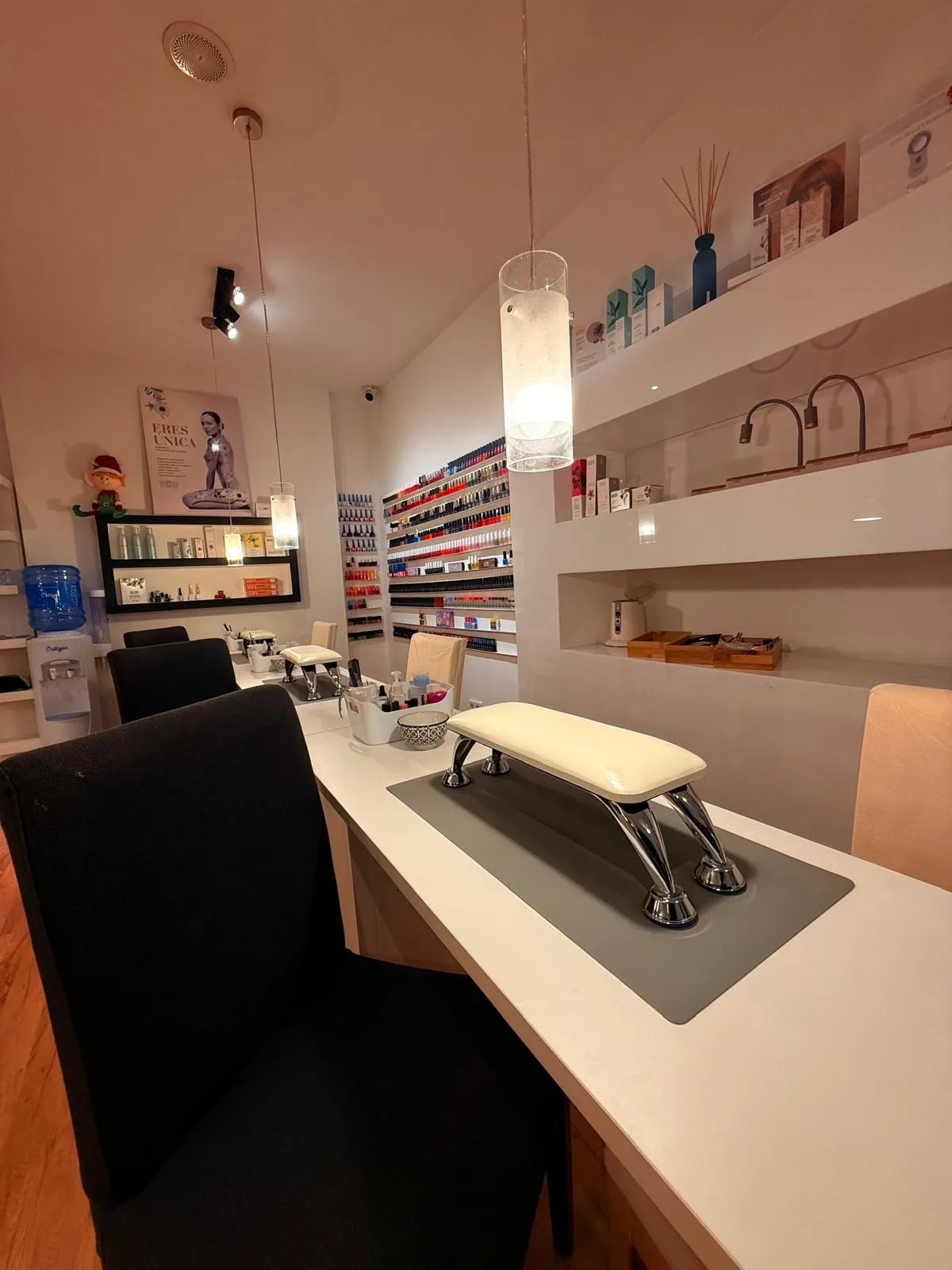 Mesa de manicura del centro con la pared de esmaltes de colores al fondo